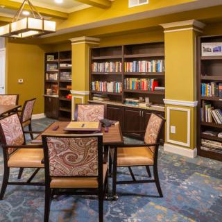 A cozy library reading room with bookshelves, a table, and chairs.
