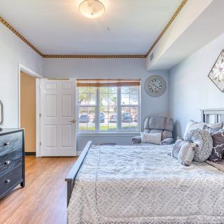 A well-lit bedroom featuring a neatly made bed, a dresser, and a large window with natural light streaming in.