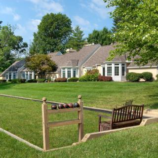 A row of houses with a well-maintained lawn and a wooden bench in a suburban setting.