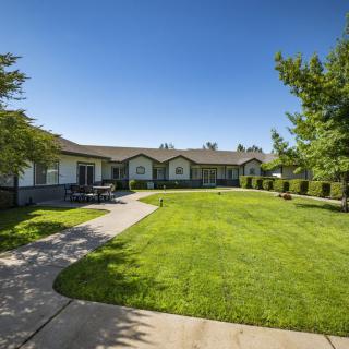 A well-maintained residential building with a lush green lawn and a pathway on a sunny day.