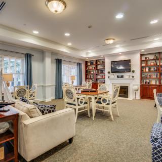 A cozy and well-furnished living room with bookshelves, a fireplace, and multiple seating areas.