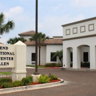 Exterior view of a medical center with a sign and landscaped entrance.
