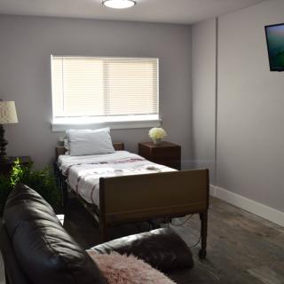 A simple hospital room with a bed, window, and television.