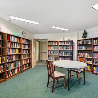 A quiet reading area in a library featuring shelves filled with books and a table with chairs.