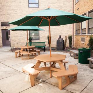 A cozy outdoor courtyard featuring wooden picnic tables with green umbrellas.