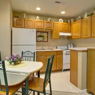 A cozy kitchen with wooden cabinets, a dining table with chairs, and essential appliances.