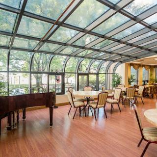 A bright and inviting sunroom dining area featuring elegant furnishings and a grand piano.
