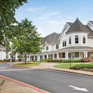 A picturesque suburban neighborhood with white houses lined along a tree-shaded street.