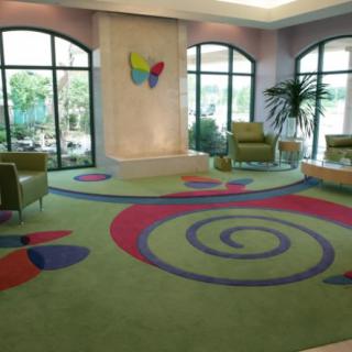 A vibrant waiting area with colorful carpet and ample seating near large windows.