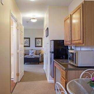 A small kitchen area with wooden cabinets leading to a hallway and a living space.
