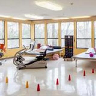 A bright rehabilitation room equipped with various exercise and therapy equipment.