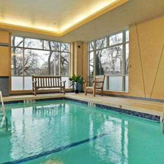 A serene indoor swimming pool area featuring wooden benches and large windows.