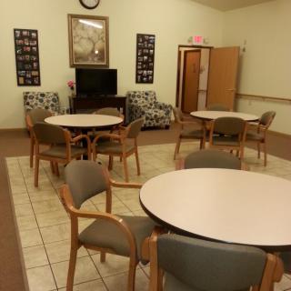 A communal room with tables, chairs, and a television set.