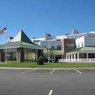 A healthcare facility with a flag in front and a clear blue sky above.