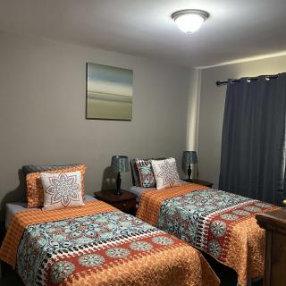 A cozy bedroom featuring twin beds with colorful bedding, complemented by lamps and dark curtains.