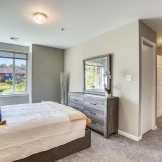 A cozy bedroom with a bed, dresser, and large window.