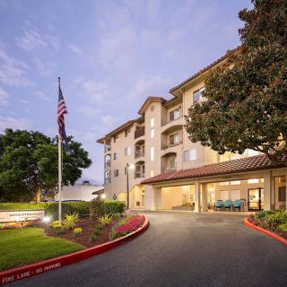 An evening view of a hotel entrance with a flagpole and landscaped surroundings.