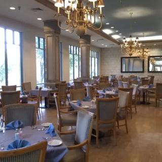 An elegant dining room with neatly arranged tables and chairs, adorned with chandeliers.