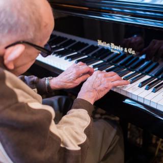 An elderly person playing the piano.