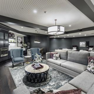 A modern living room with a cozy gray color scheme, featuring comfortable seating and elegant lighting.
