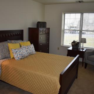 A cozy bedroom interior with a neatly made bed and yellow bedding.