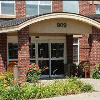 A brick building entrance with decorative landscaping and flowers.