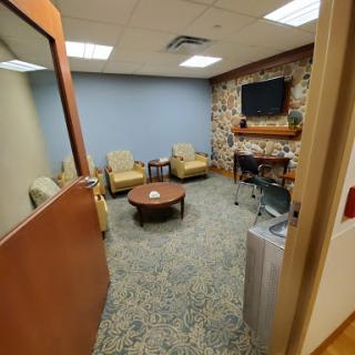 A cozy waiting room featuring comfortable seating, a television, and a warm atmosphere.