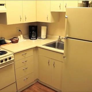 A compact kitchen with a stove, refrigerator, sink, and cabinets.