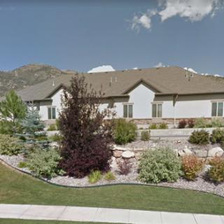 A beautifully landscaped residential area with a single-story house and mountains in the background.