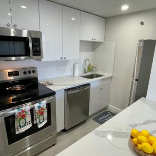 A modern kitchen featuring sleek white cabinets and stainless steel appliances, with a bowl of fresh lemons on the countertop.
