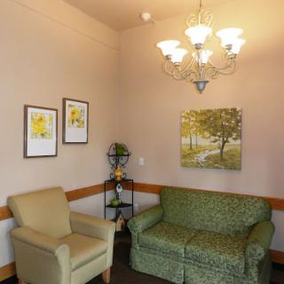 A cozy living room corner featuring a green sofa, an armchair, and artwork on the walls.