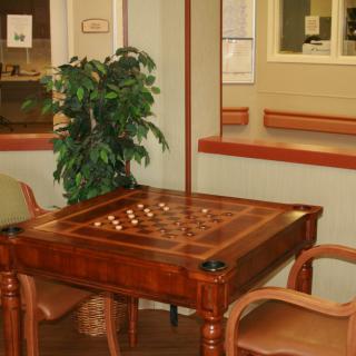 A cozy indoor setting featuring a wooden game table with checkers and chairs.