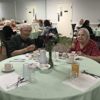 Elderly individuals enjoying a meal together in a communal dining setting.