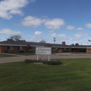 A single-story brick building with a sign on the lawn under a partly cloudy sky.
