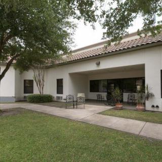 A view of a building exterior with a small garden and seating area.