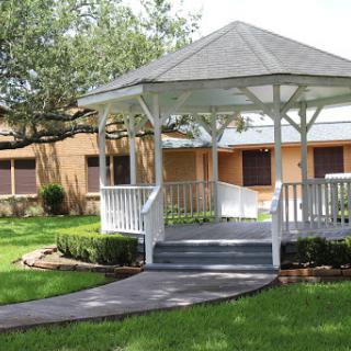 A charming white gazebo surrounded by well-maintained greenery, offering a peaceful outdoor space.