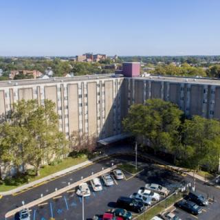 An aerial view of a hotel building surrounded by a parking lot and greenery.