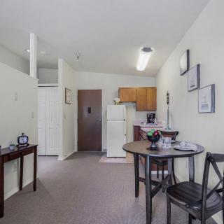 A cozy apartment interior featuring a small kitchen and dining area with a table and chairs.