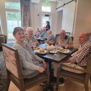 A joyful gathering of seniors enjoying a meal together in a communal dining setting.