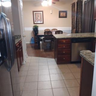 A view of a kitchen leading into a dining area, featuring stainless steel appliances and wooden cabinets.