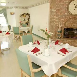 A cozy dining room with neatly set tables and a fireplace.