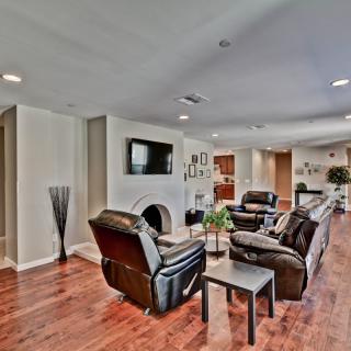 A modern living room with leather couches and a television on the wall, featuring hardwood floors and stylish decor.