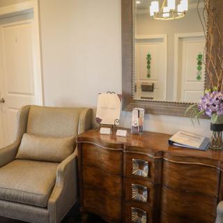 A cozy living room corner featuring a comfortable armchair and a wooden dresser with decorative items.