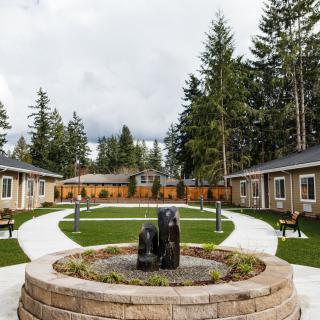 A serene courtyard with a central fountain, surrounded by pathways, benches, and lush greenery.
