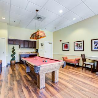 A game room featuring a billiard table with overhead lighting and comfortable seating.