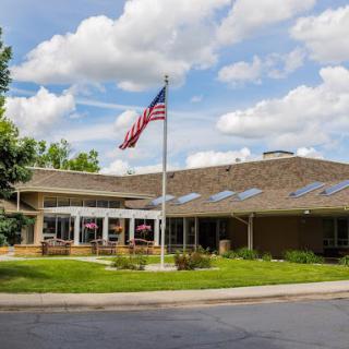 A single-story building with an American flag in front and a cloudy sky overhead.