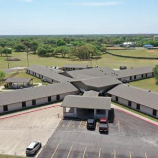 Aerial view of a building complex with a parking lot in a rural setting.
