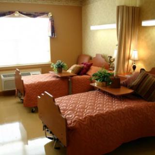 A cozy hospital room with two neatly made twin beds, bedside tables, and decorative plants.