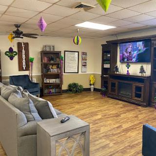 A cozy living room setup featuring comfortable seating, decorative shelves, and a large television.