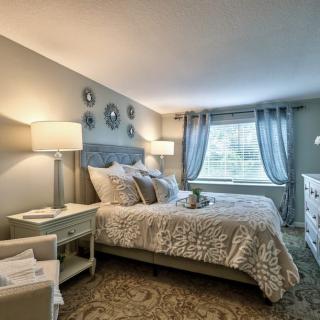 A cozy and well-decorated bedroom with a comfortable bed, elegant lamps, and soft curtains.